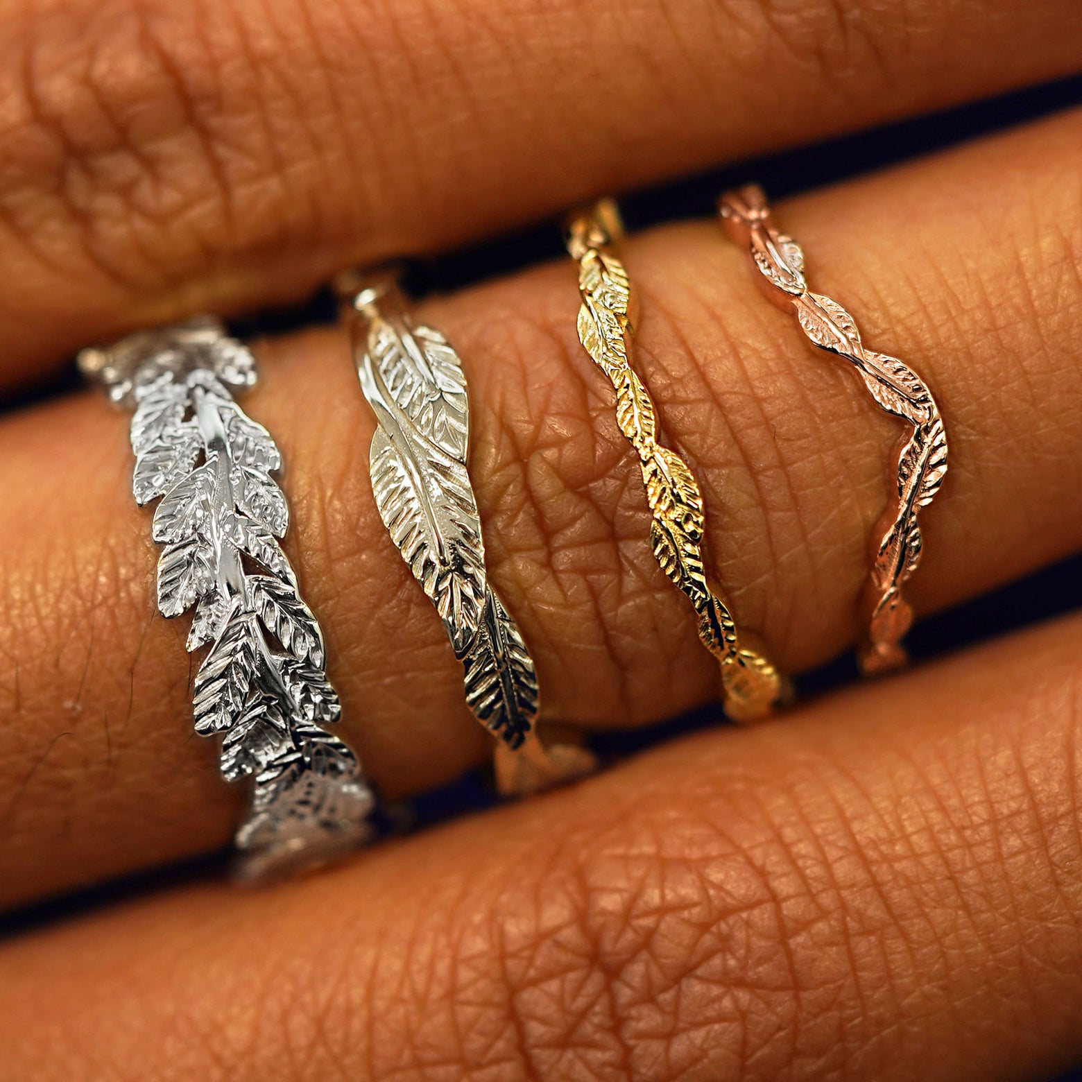 A Chevron Leaf Band, Thin Leaves Band, Thick Leaves Band, and Double Leaves Band stacked in four different gold colors