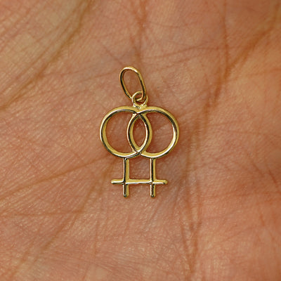 A solid gold Lesbian Symbol Charm for chain resting in a model's palm