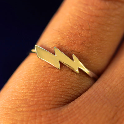 Close up view of a model's hand wearing a yellow gold Lightning Bolt Ring