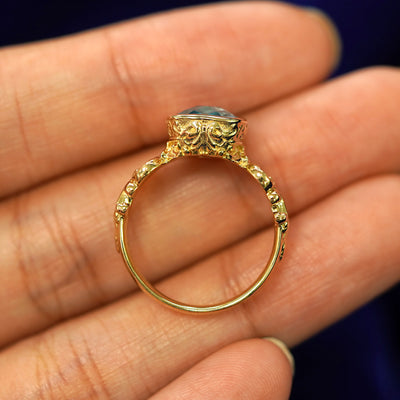 A yellow gold London blue topaz Royalty Ring in a model's hand showing the thickness of the band