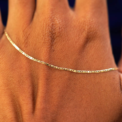 A solid gold Valentine Bracelet resting on the back of a model's hand