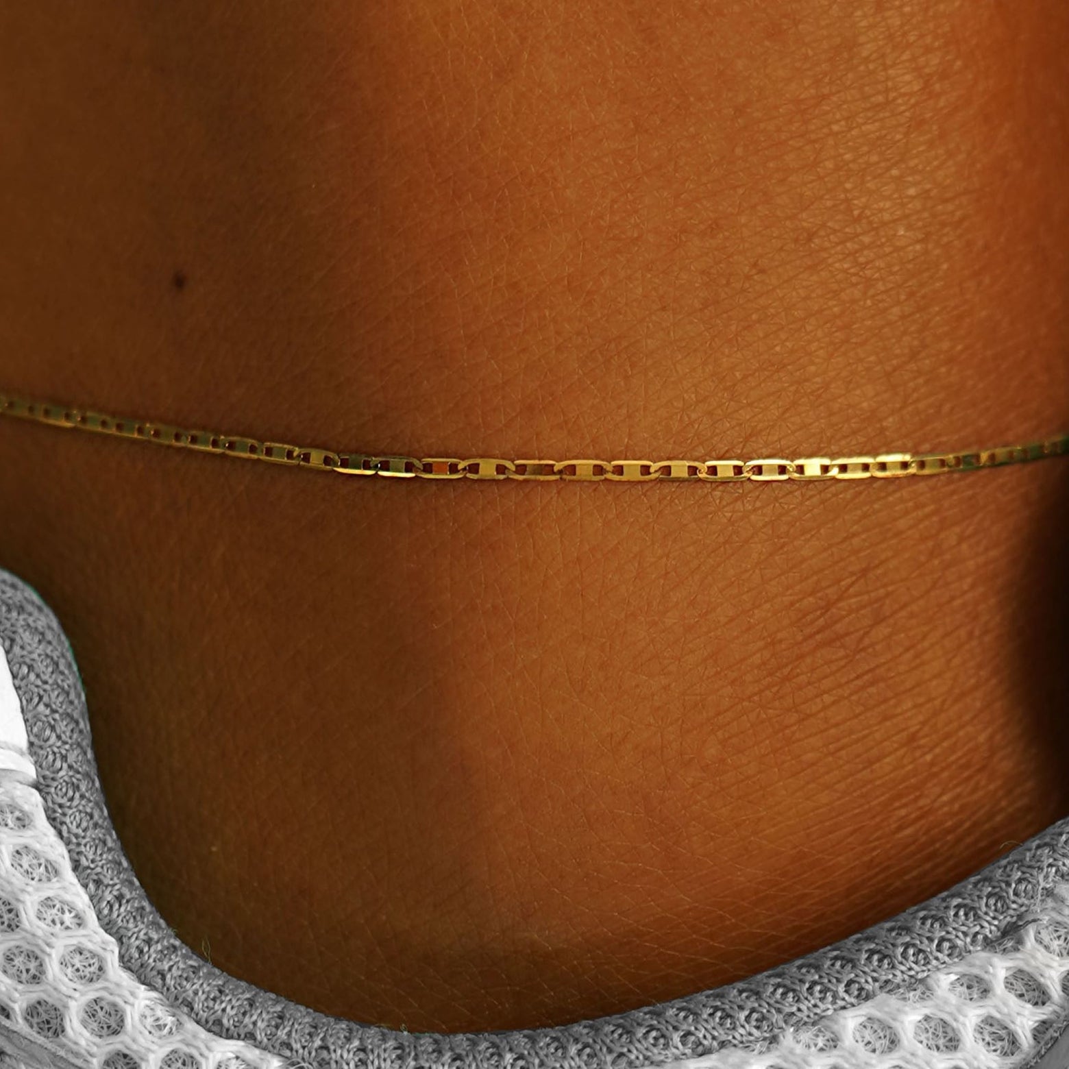 Close up view of a models ankle wearing a 14k yellow gold Valentine Anklet