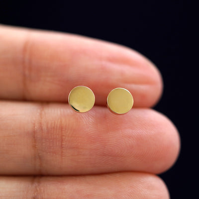 A model's hand holding a pair of recycled 14k gold Medium Circle Earrings