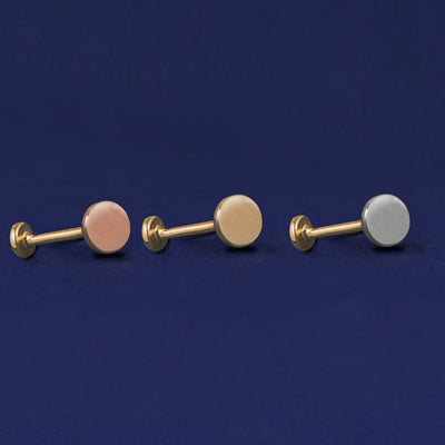 Three versions of the Medium Circle Flatback Piercing shown in options of rose, yellow, and white gold