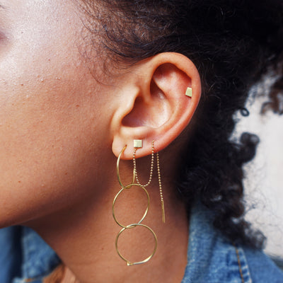 Close up view of a model's ear wearing three Medium Hoops looped together to form a long dangle earring