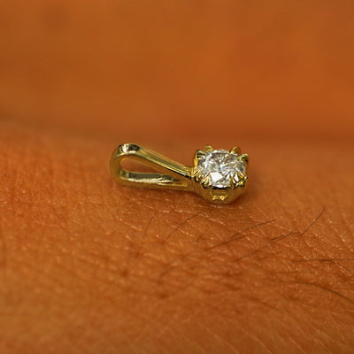 A 14k yellow gold Moissanite Charm for chain resting on the back of a model's hand