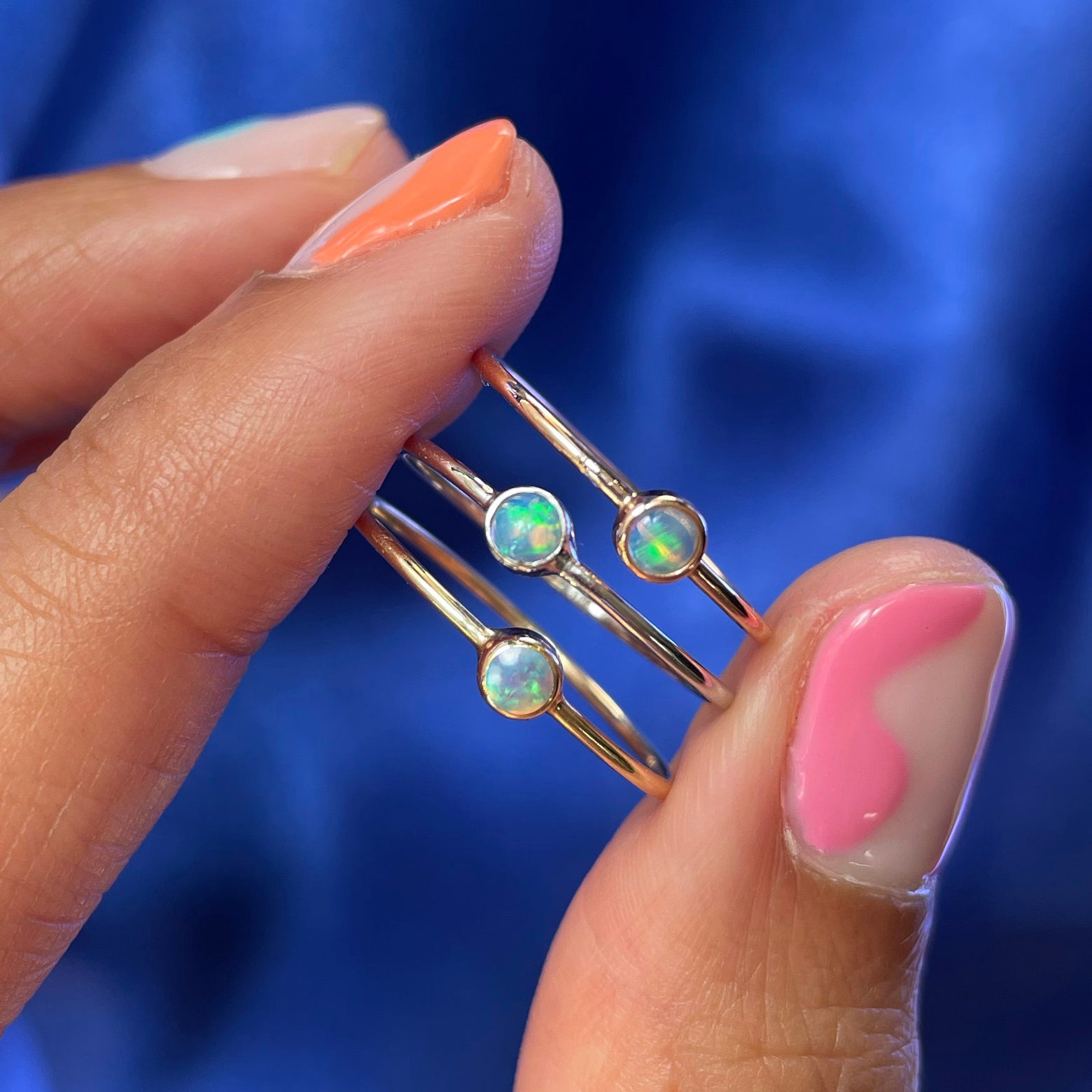 A model holding a stack of three Opal Rings between their fingers