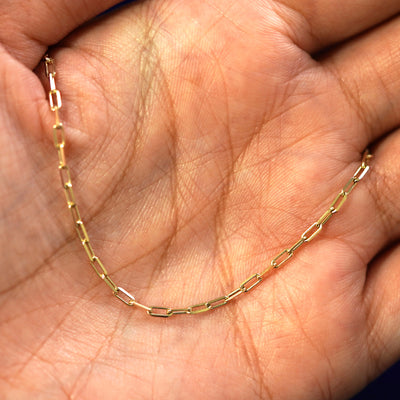 A yellow gold Butch Anklet draped on a model's palm