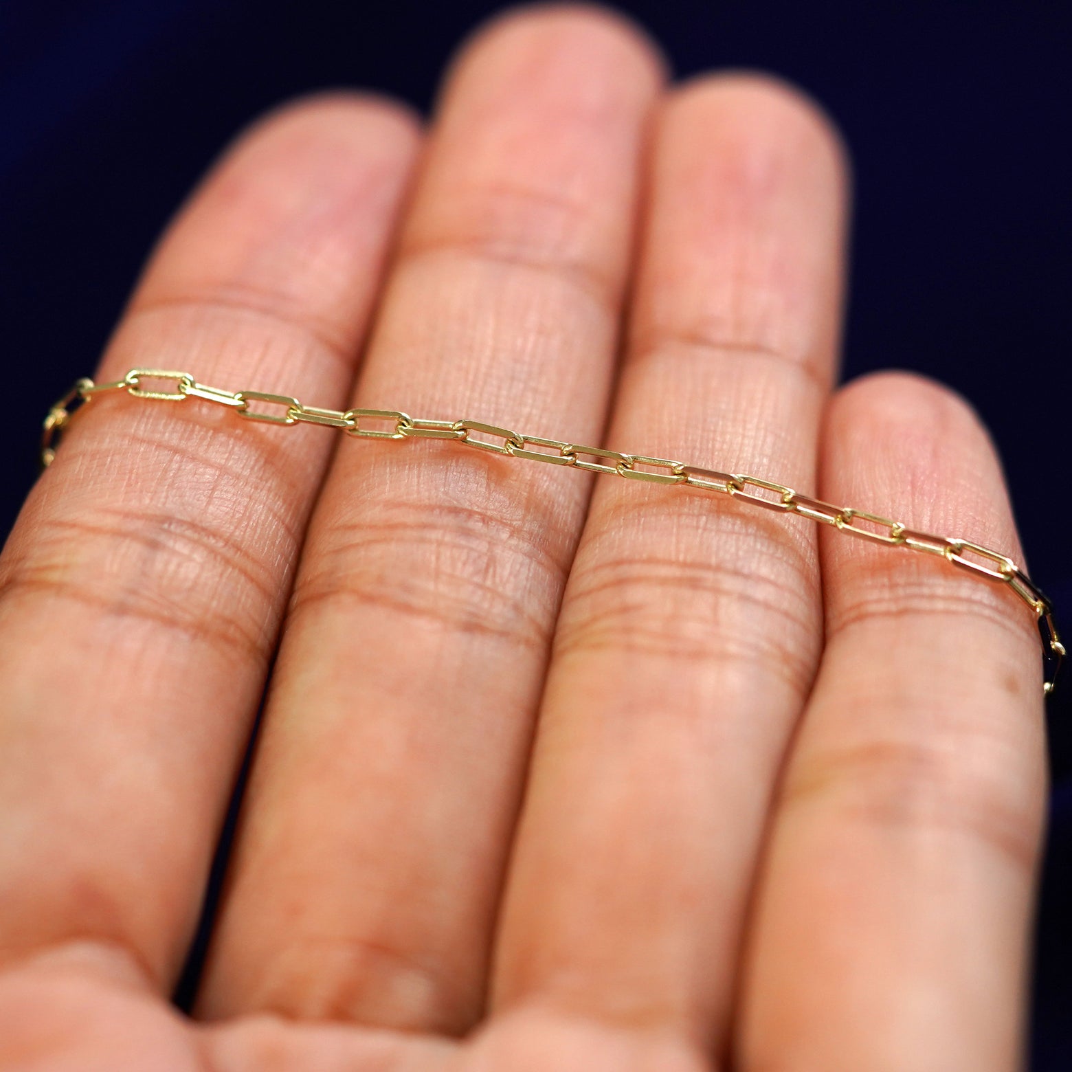 A yellow gold Butch Chain resting on a model's fingers