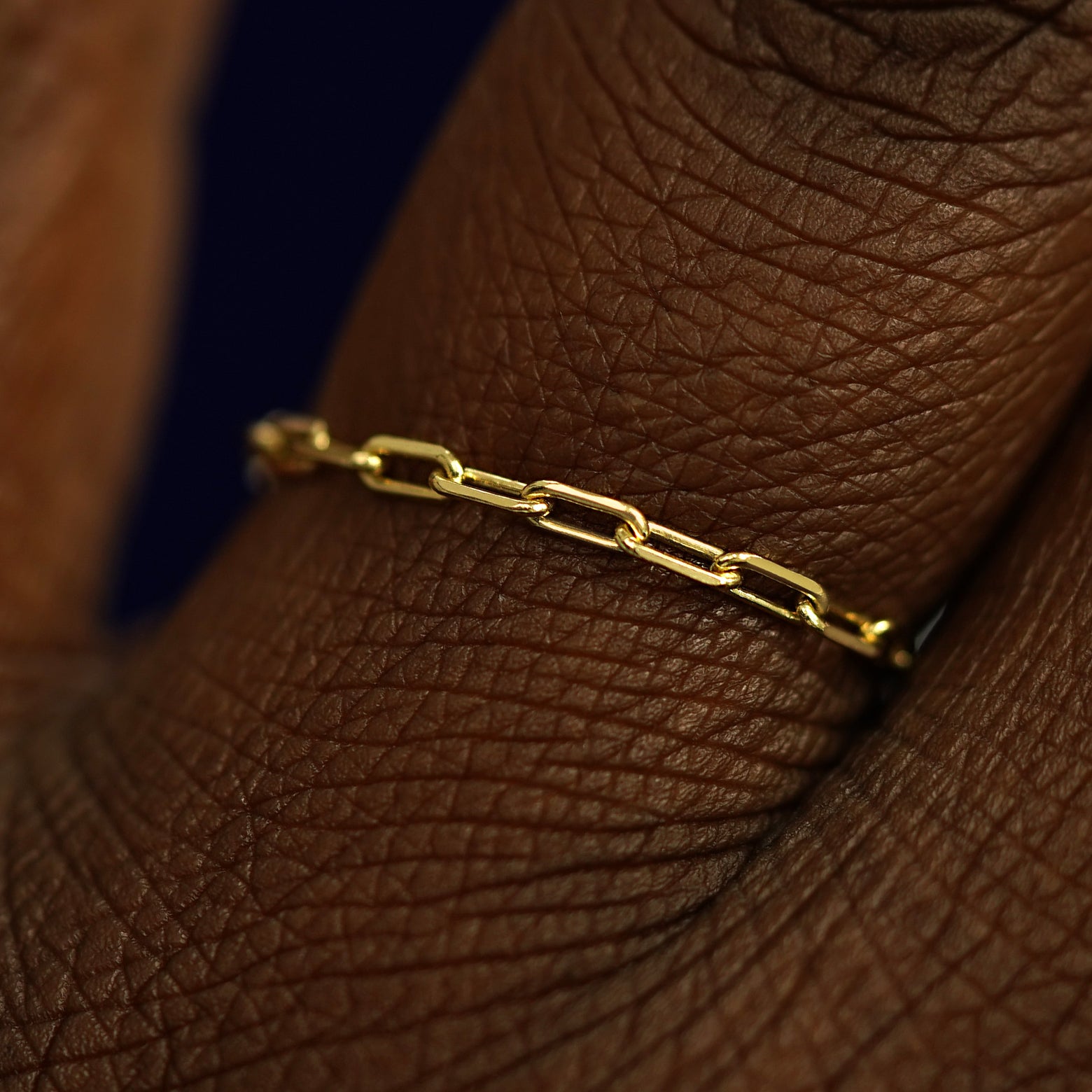 Close up view of a model's fingers wearing a 14k yellow gold Butch Chain Ring