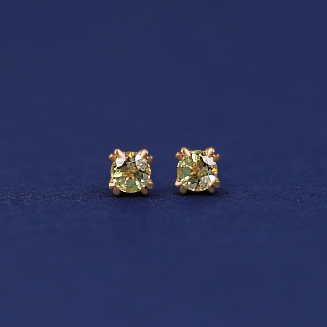 A pair of 14 karat gold studs earrings with 3 millimeter round Peridot gemstones