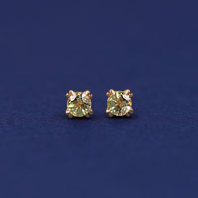 A pair of 14 karat gold studs earrings with 3 millimeter round Peridot gemstones