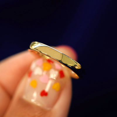 A model holding a 14k gold Mix Mirror Band tilted to show the side of the ring