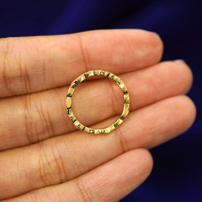 A yellow gold Thin Leaves Band in a model's hand showing the thickness of the band