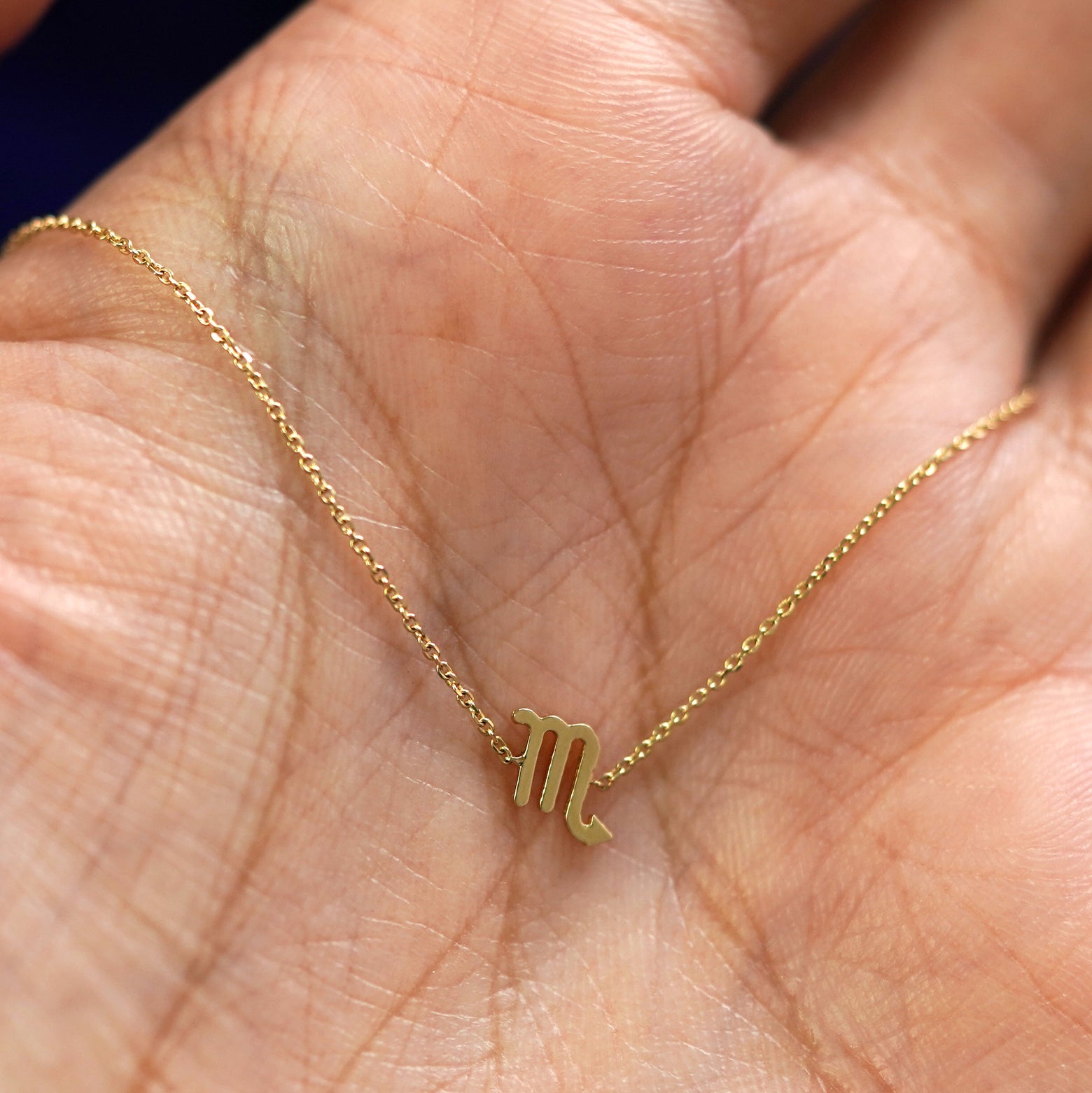 A yellow gold Scorpio Horoscope Bracelet draped on a model's palm