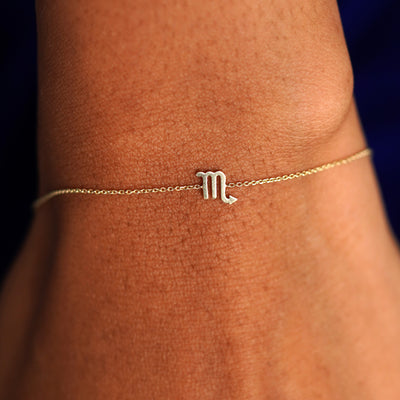 A model's wrist wearing a solid yellow gold Scorpio Horoscope Bracelet