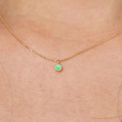 Close up view of a model's neck wearing a solid 14k yellow gold Jade necklace