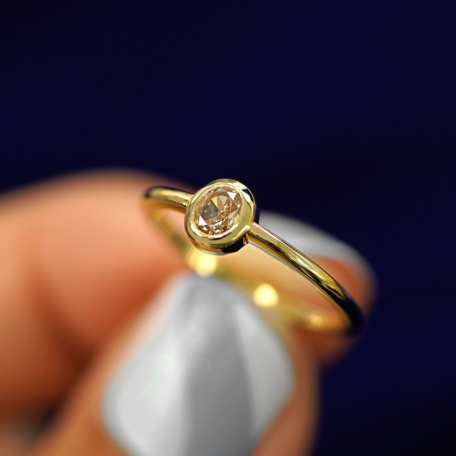 A model holding a Oval Champagne Diamond Ring tilted to show the details of the thick bezel setting