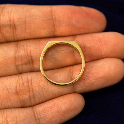 A yellow gold Rectangular Signet Ring in a model's hand showing the thickness of the band