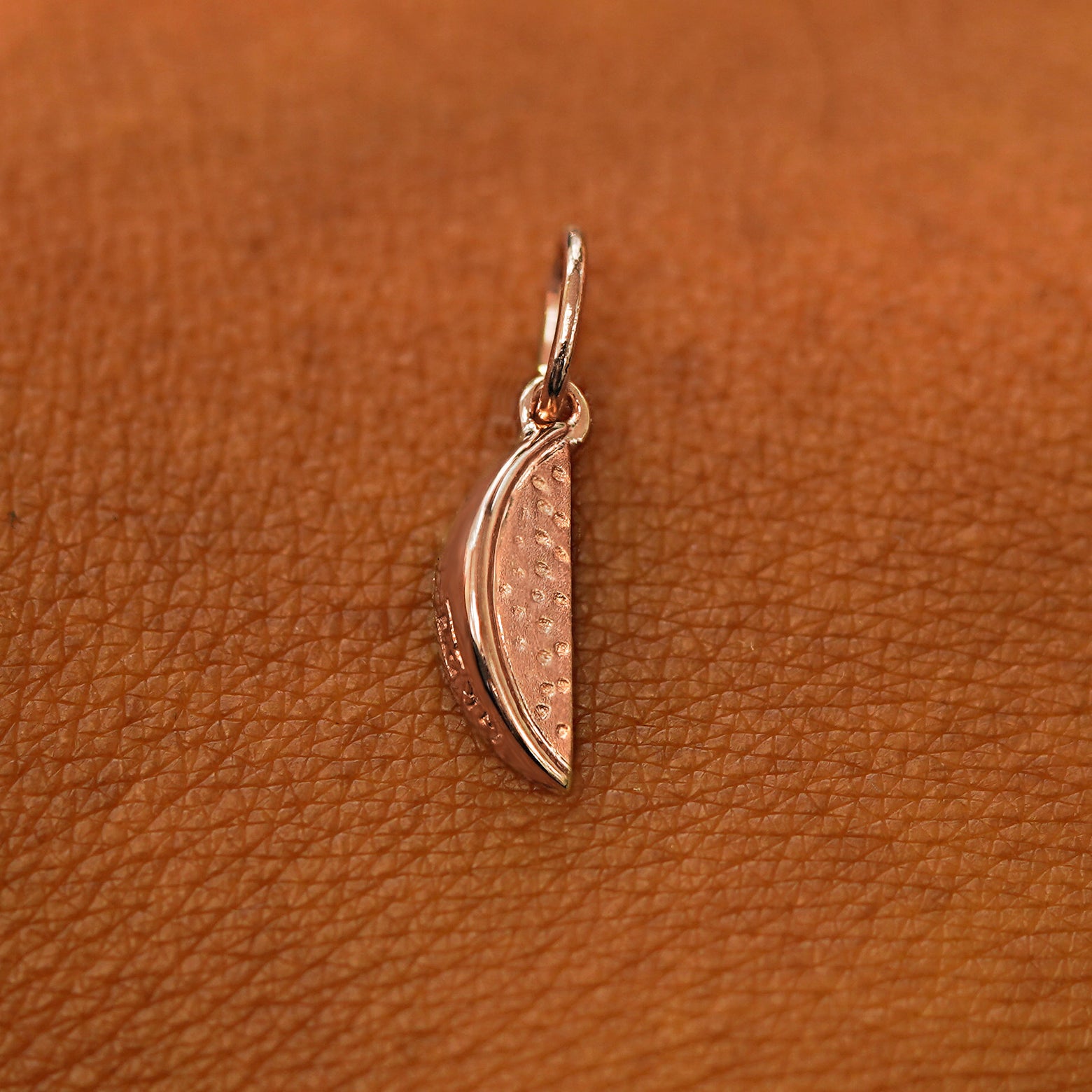 A solid 14k rose gold Watermelon Charm resting on the back of a model's hand