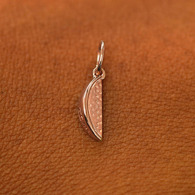 A solid 14k rose gold Watermelon Charm resting on the back of a model's hand