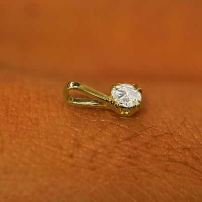 A 14k yellow gold Rose Cut Diamond Charm for chain resting on the back of a model's hand