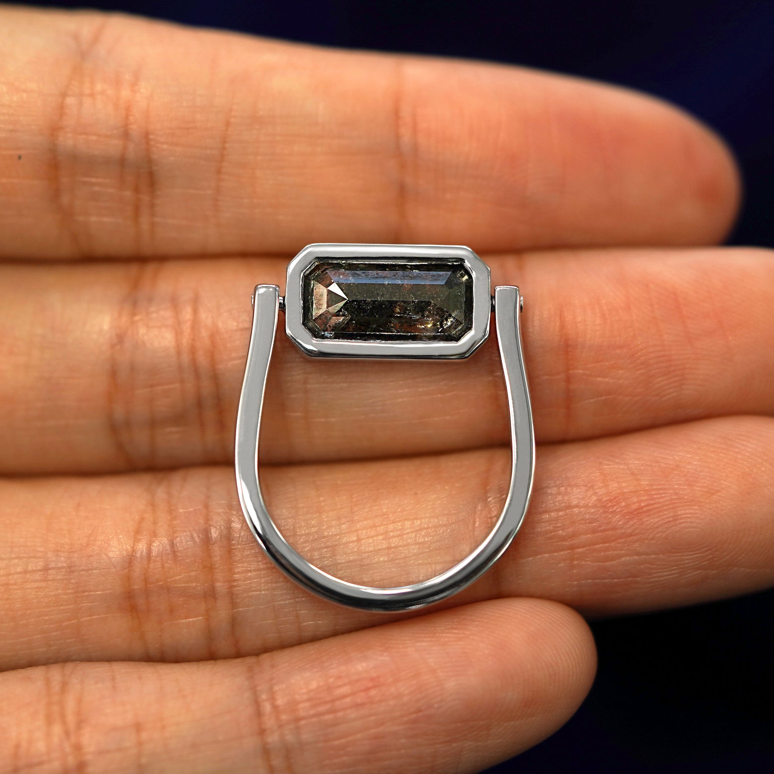 A white gold Salt and Pepper Diamond Spinner Ring in a model's hand with the diamond spun to the side