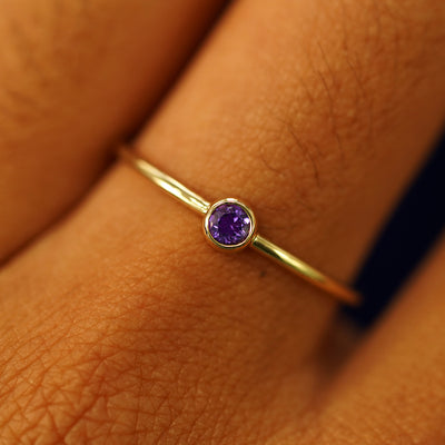 Close up view of a model's hand wearing a 14k yellow gold Amethyst Ring