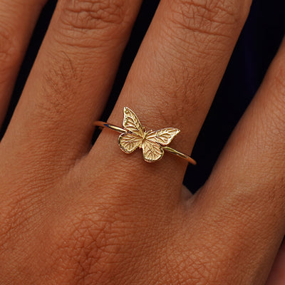 Close up view of a model's hand wearing a yellow gold Butterfly Ring
