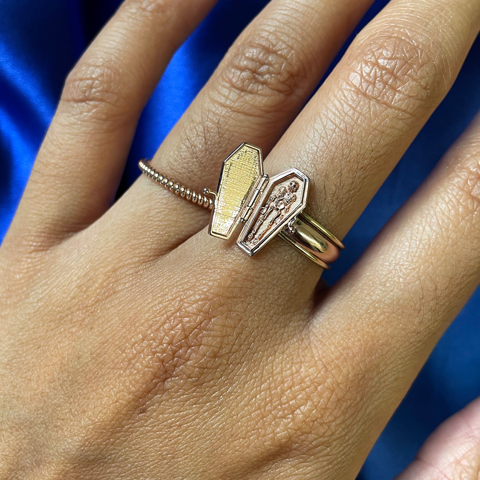 Close up view of a model's hand wearing an open Coffin Ring and a Rope Ring