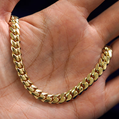 A yellow gold Miami Cuban Chain draped on a model's palm