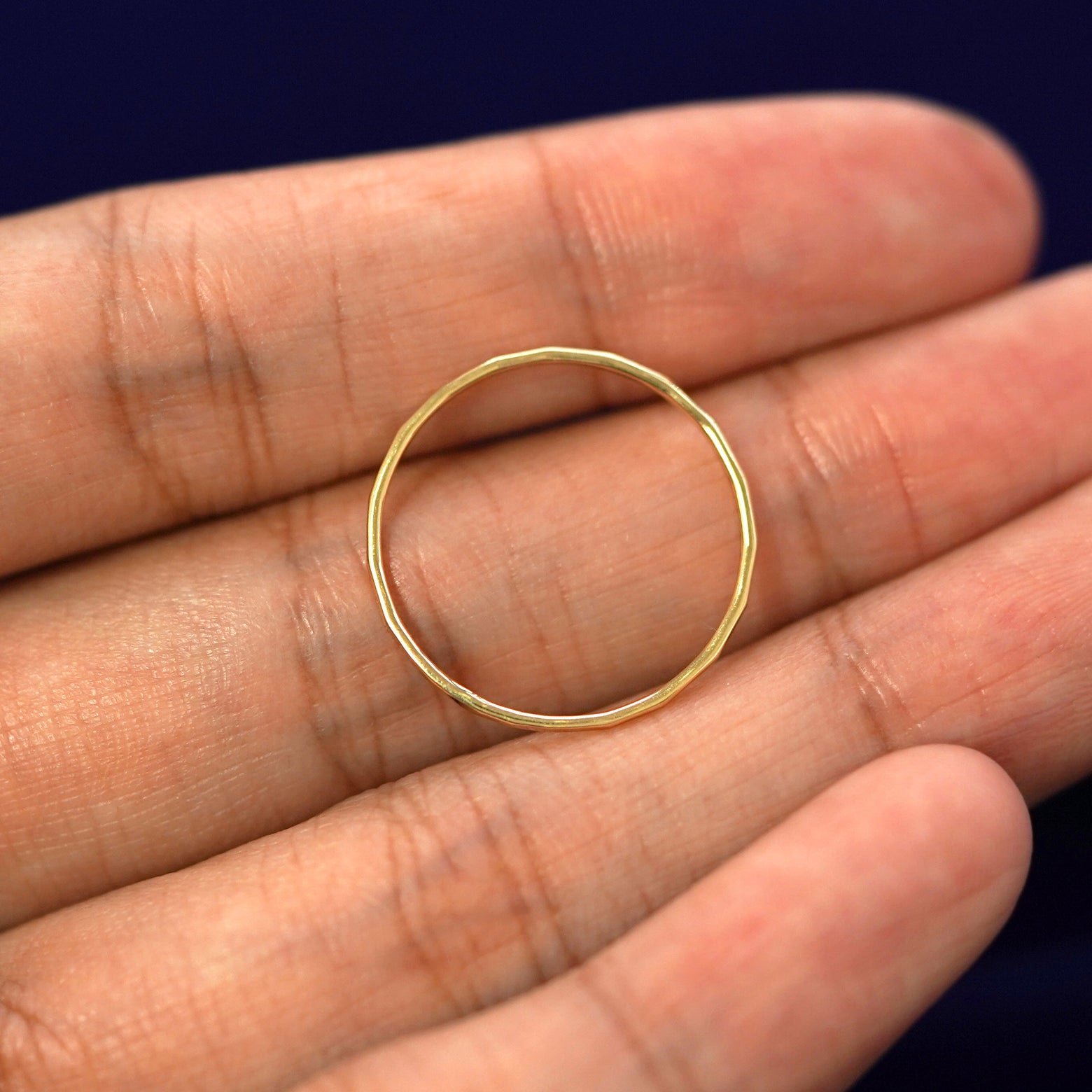 A yellow gold Hammered Ring in a model's hand showing the thickness of the band