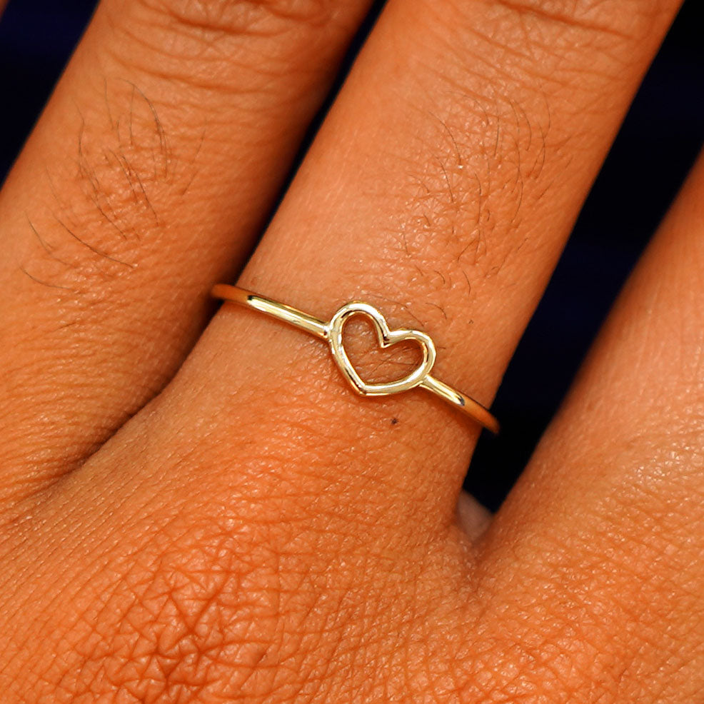 Close up view of a model's hand wearing a solid gold Heart Ring