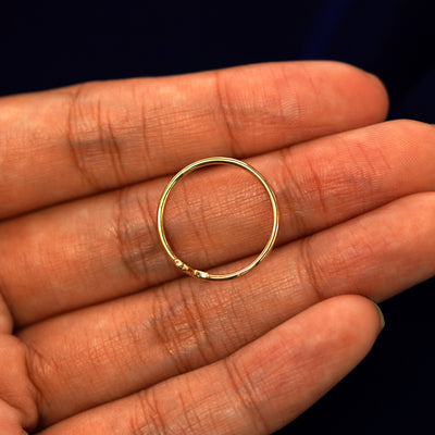 A yellow gold initial letter N ring in a model's hand showing the thickness of the band