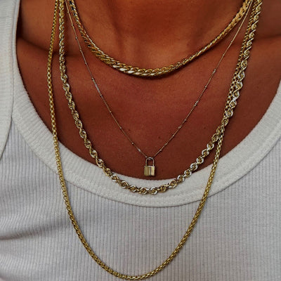 A model wearing a Curb Chain, a Beaded Essential Chain with Lock Charm, a Thick Rope Chain and a Rounded Box Chain layered