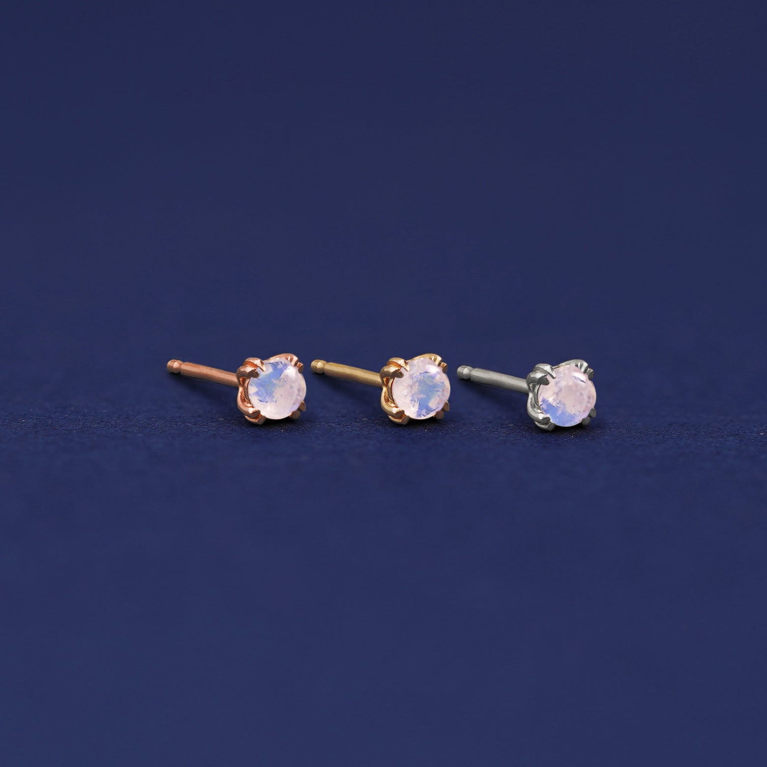 Three versions of the Moonstone Earring shown in options of rose, yellow, and white gold