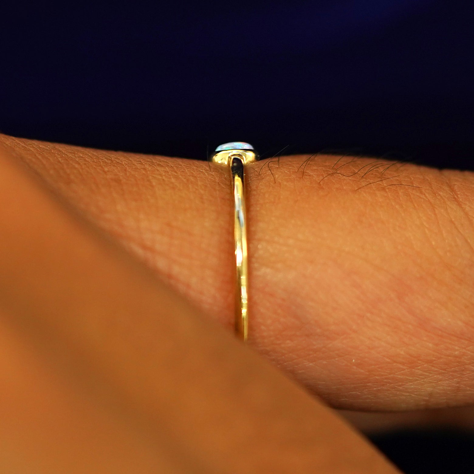 Side view of a model's finger wearing a yellow gold Opal Ring