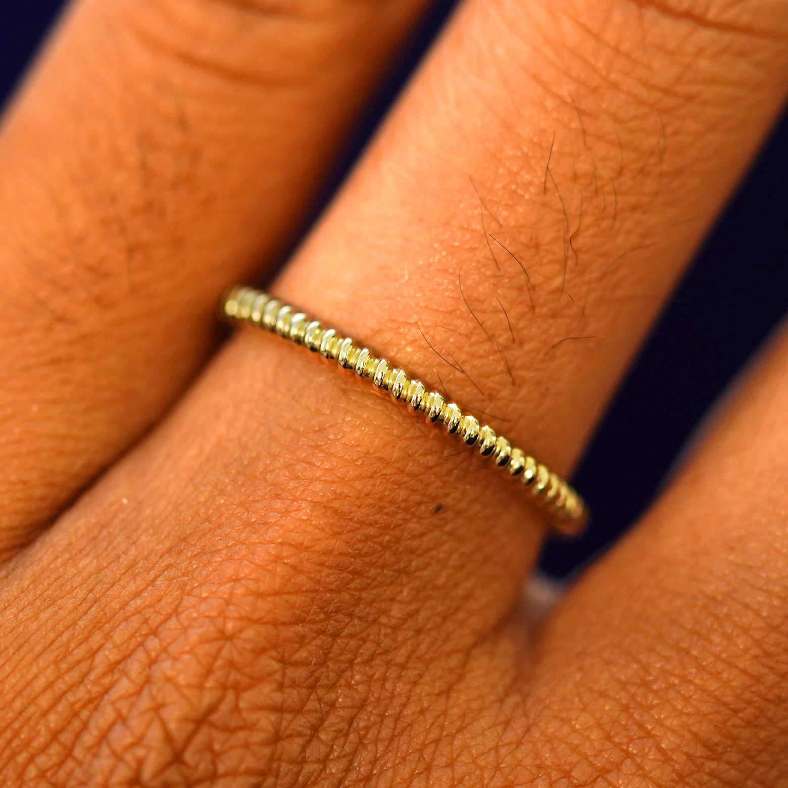 Close up view of a model's hand wearing a solid gold Rope Ring