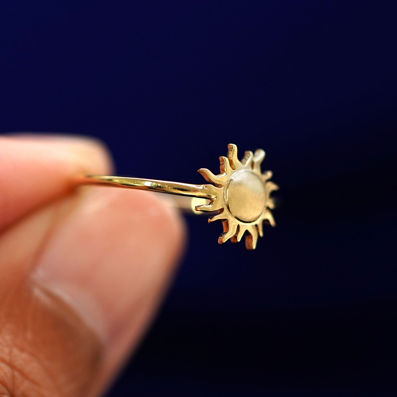 A model holding a Sun Ring tilted to show the side of the ring