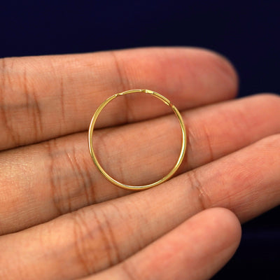 A yellow gold Tanlah Ring in a model's hand showing the thickness of the band