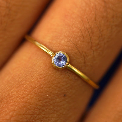 Close up view of a model's fingers wearing a 14k yellow gold Tanzanite Ring