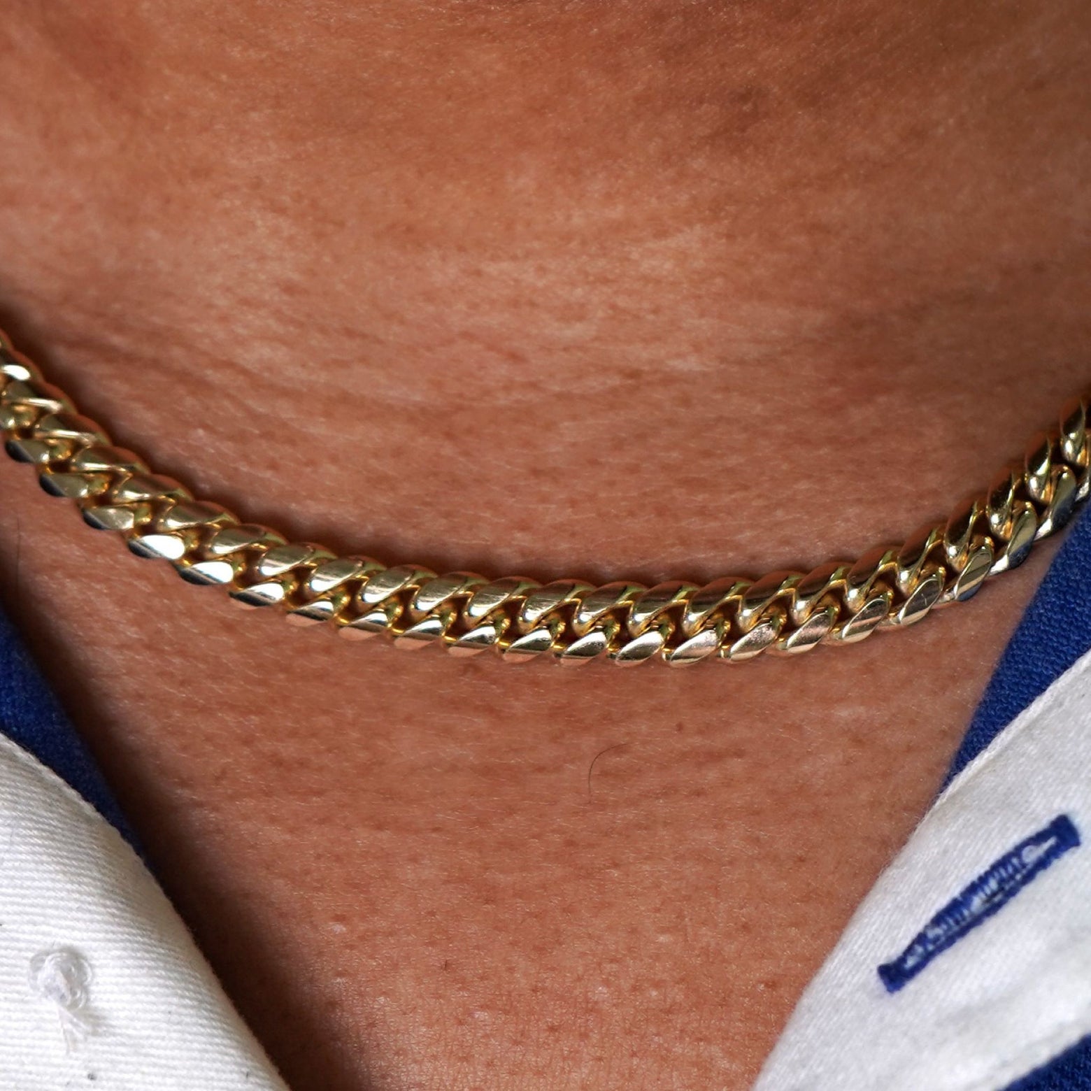 Close up view of a model's neck wearing a yellow gold Miami Cuban Chain