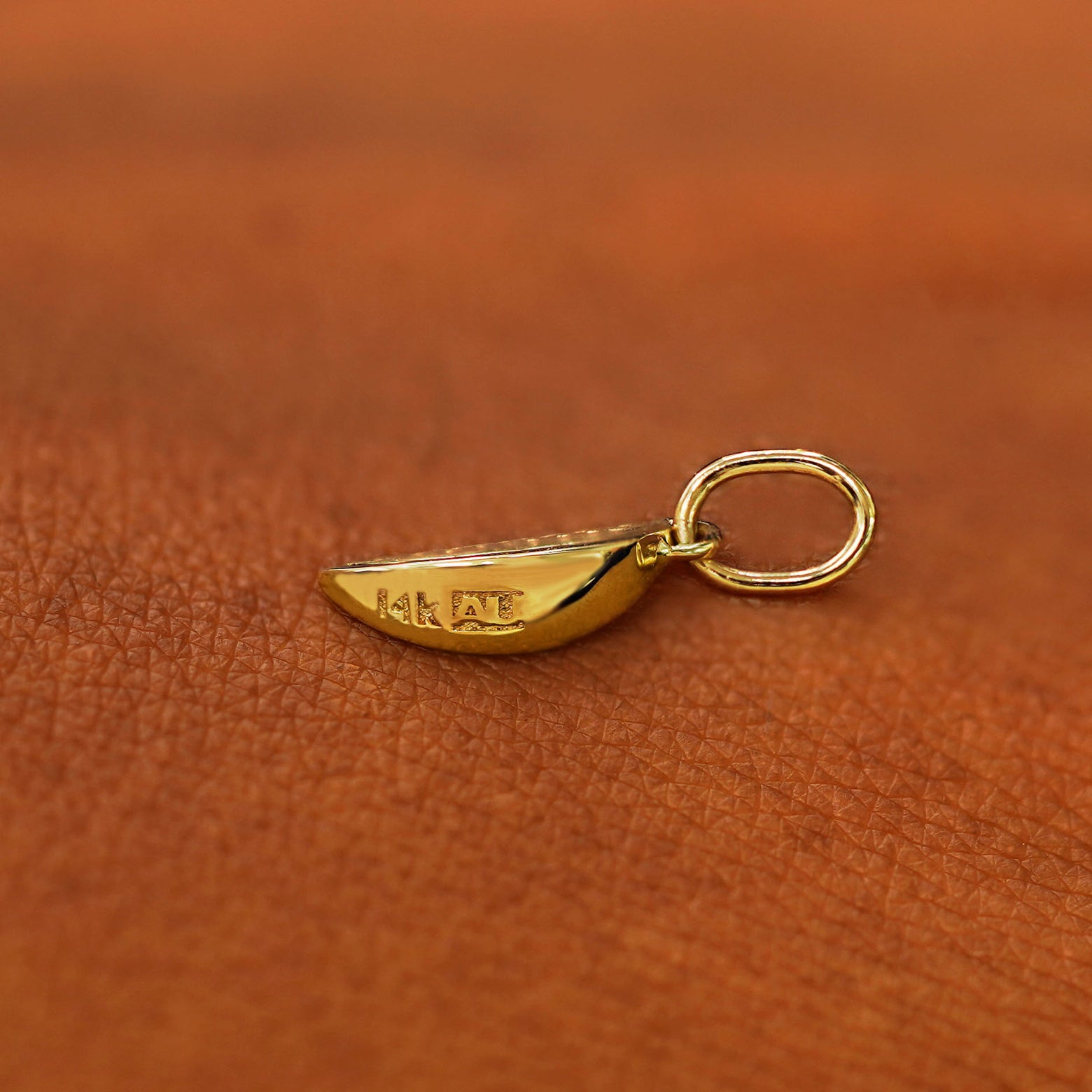 Back view of a solid 14k yellow gold Watermelon Charm resting on the back of a model's hand