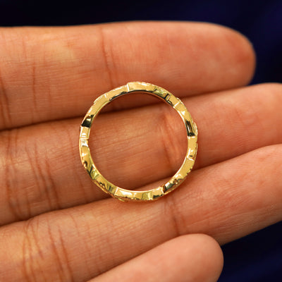 A yellow gold Thick Leaves Band in a model's hand showing the thickness of the band