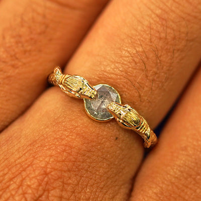 Close up view of a model's fingers wearing a 14k yellow gold Salt and Pepper Diamond Guardian Snakes Ring