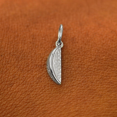 A solid 14k white gold Watermelon Charm resting on the back of a model's hand