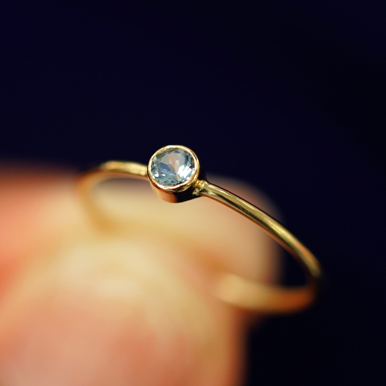 A model holding an Aquamarine Ring tilted to show the bezel setting