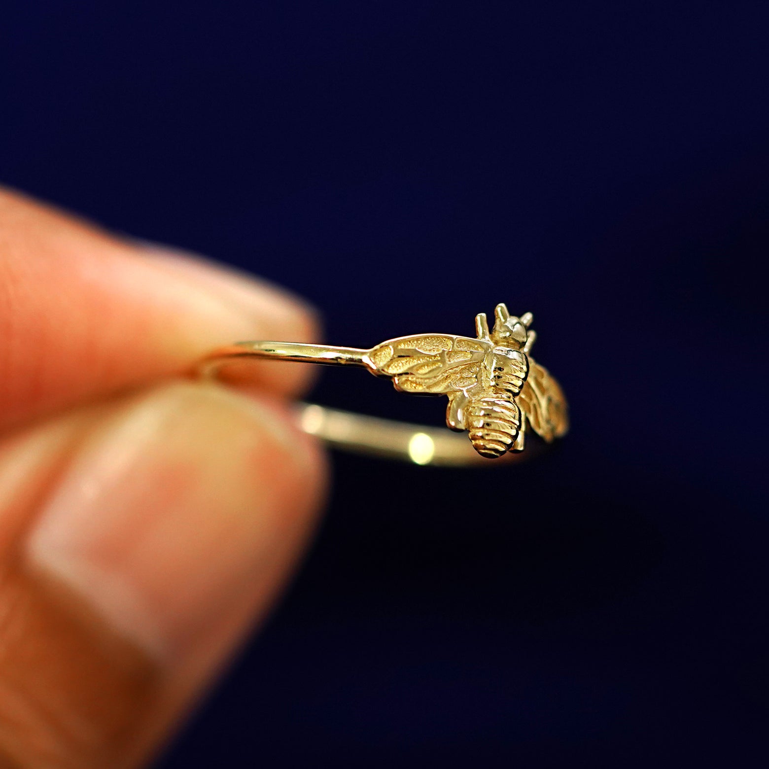 A model holding a Bee Ring tilted to show the side of the ring