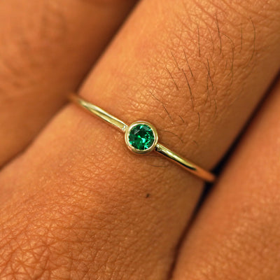 Close up view of a model's fingers wearing a 14k yellow gold Emerald Ring