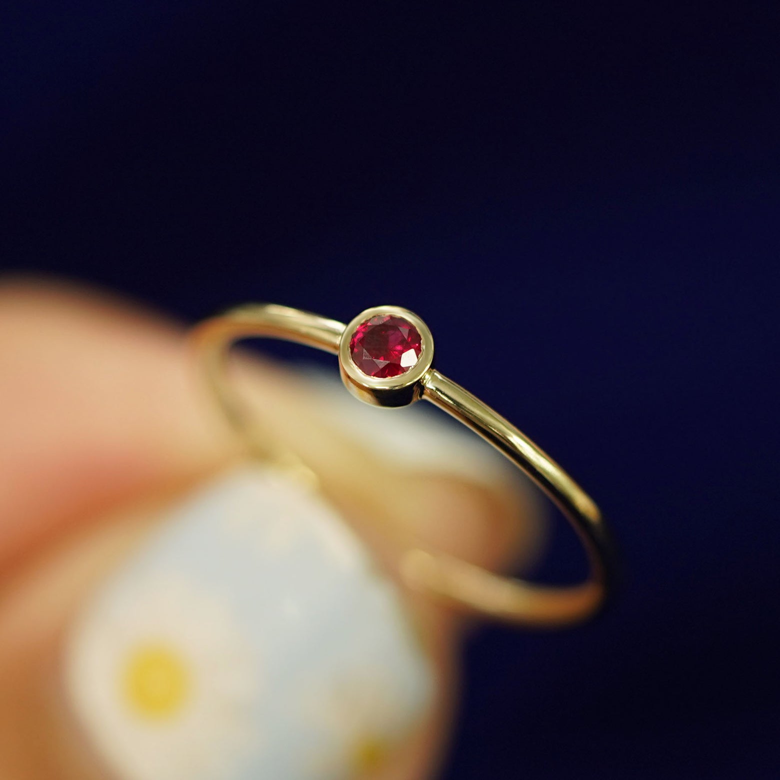 A model holding a Garnet Ring tilted to show the bezel setting